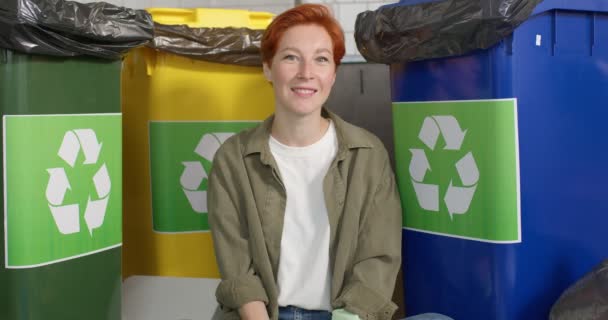 Conceito de Sustentabilidade. Mulher alegre Millennial sentado ao lado de recipientes com diferentes resíduos — Vídeo de Stock