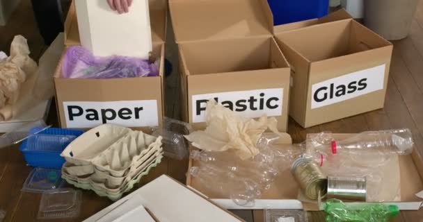 Обрізана жінка сортує відходи паперу в картонні коробки на підлозі, крупним планом — стокове відео