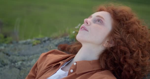 Dinlenmiş kızıl saçlı kadın dağın tepesinde tek başına dinleniyor. — Stok video