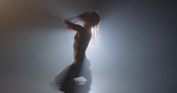 Štíhlé ženské siluety tělo sedí na podlaze v Aqua Studio v mlhavém kouřovém prostoru — Stock video