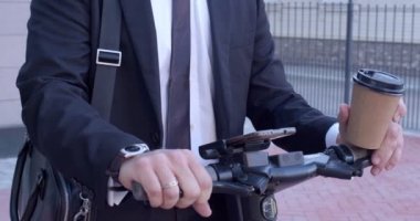 Erkek Elleri Kahvesini Tutuyor, Resmi Takım Elbiseli, Elektrikli Tekme Scooter ile Duruyor