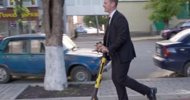 Homem de negócios sorridente de terno montando uma scooter elétrica em reunião de negócios. em cidade — Vídeo de Stock