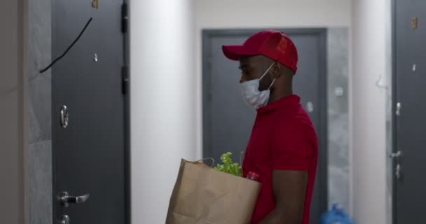 Entrega de compras.Afro mensajero masculino individuo que da el paquete de comida a la mujer del cliente. — Vídeo de stock