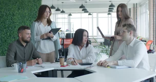 Empresarios que se reúnen alrededor de la mesa en la oficina moderna teniendo una buena charla — Vídeos de Stock