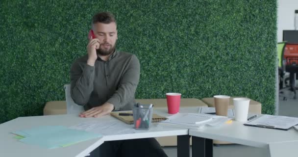 Modern ofiste masa başında çalışan genç ve stresli bir iş adamı — Stok video