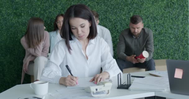 Attraktiv kaukasisk ung säker affärskvinna sitter vid kontorsbordet med kollegor — Stockvideo