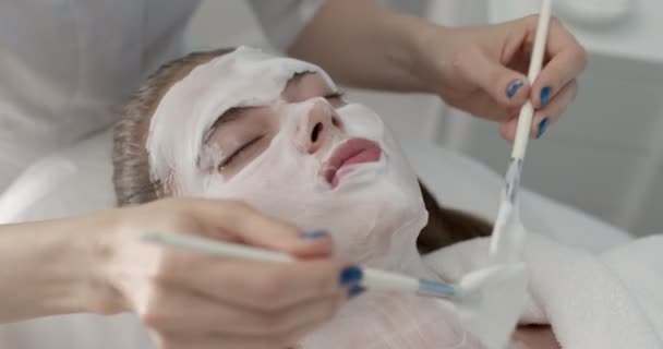 Close up of beautiful young woman lying with closed eyes in spa or beauty salon — Stock Video