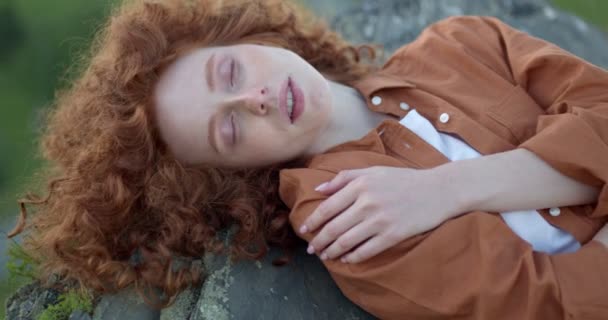 Femme rousse rêveuse reposant seule sur le sommet d'une falaise dans la montagne — Video