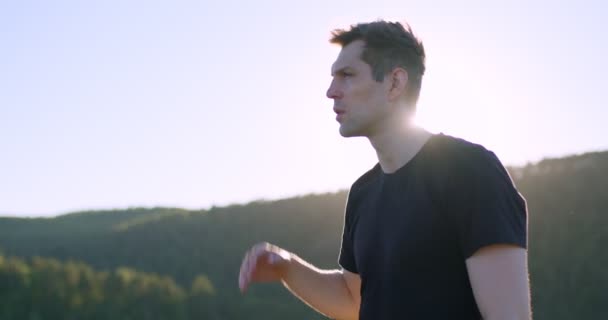 Caucasian handsome good-looking male stands in mountains alone looking at side — Stock Video