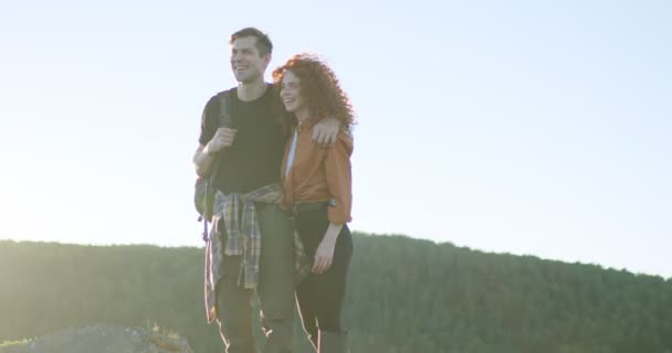 Slim joven mujer y hombre de pie abrazándose en las montañas al atardecer en la noche — Vídeo de stock