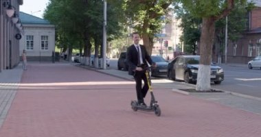 İş toplantısında elektrikli scooter kullanan takım elbiseli neşeli bir iş adamı. Sokakta