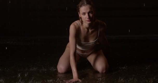 Roztomilé fit dáma v plavkách sedět na podlaze stříkající vodu, hledá pózování na kameru — Stock video