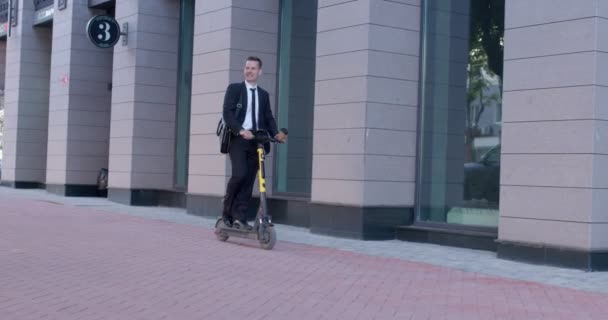 Moderner Geschäftsmann mit Elektroroller auf dem Weg zur Arbeit in der Stadt — Stockvideo
