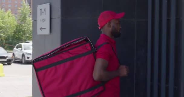 Termal çantalı bir teslimatçı kapı zilini çalıyor, dahili telefonu çeviriyor. — Stok video