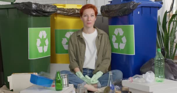 Duurzaamheidsconcept. Serieuze Millennial vrouw zit naast containers met verschillende afvalstoffen — Stockvideo