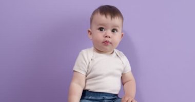 Güzel küçük şeker prenses yan yana oturur tatlı tatlı gülümser ve mor renkte izole olur.