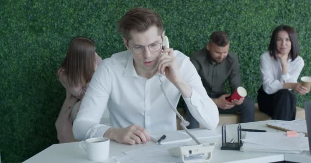 Gelukkig Kaukasische man praten over de telefoon, vieren de overwinning, in modern kantoor met collega 's — Stockvideo