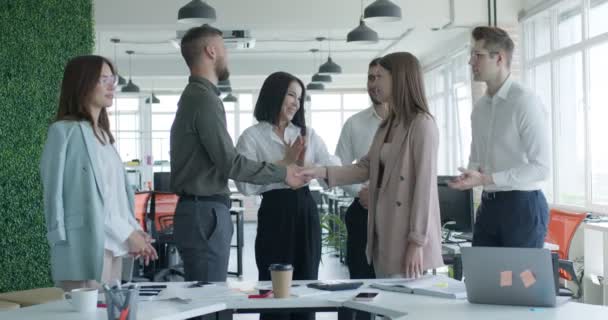 Zakenmensen schudden elkaar de hand terwijl collega 's klappen en applaudisseren — Stockvideo