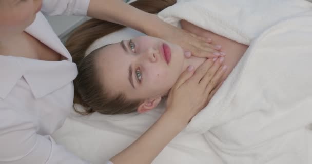 美容師は若い女性のための化粧品の顔の治療を行う準備. — ストック動画