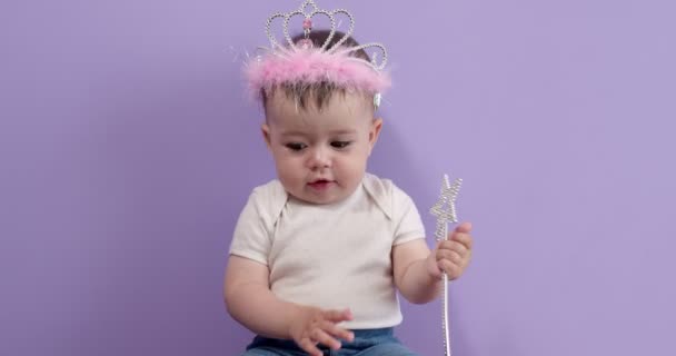 Cute little girl with princess wand. Portrait of cute caucasian baby in crown isolated on purple — Stock Video