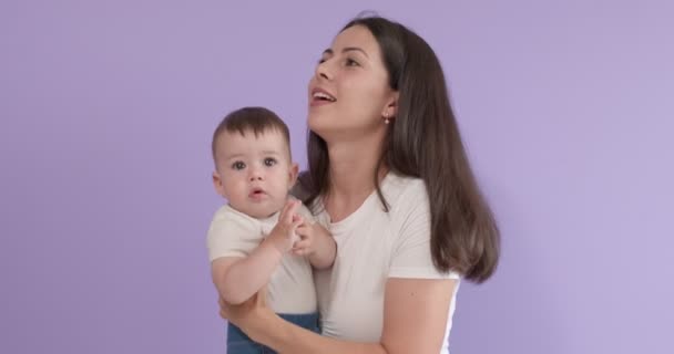 Bonita familia caucásica aislada sobre fondo púrpura, madre joven sosteniendo hija — Vídeos de Stock