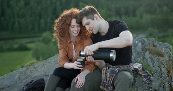 Joven está vertiendo té en la taza de novia durante el viaje, sentarse en las montañas — Vídeo de stock