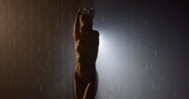 Kadın silueti koyu renkli arka planda duruyor sağanak yağmurda