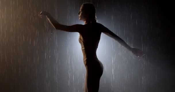 Dancer pose in the pouring rain. Wet body silhouette of young woman moving — Stock Video
