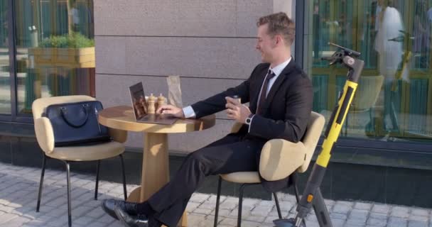 Pengusaha yang percaya diri duduk di teras kafe outdoor berselancar di internet, beristirahat — Stok Video