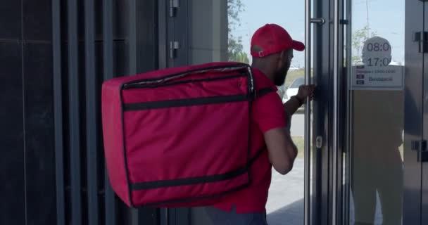 Food courier man with thermal bag ringing the doorbell, dial the intercom — Stock Video