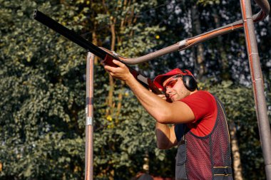 Av tüfeğiyle dış koruluğa nişan alan yakışıklı bir adam. Optik görüşlü karabina.