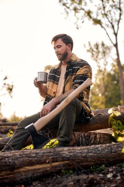 Genç ve yorgun erkek ağaç kesiminden sonra çay içiyor, Lamberjack dinleniyor.