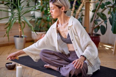 Kısa saçlı kadın Palo Santo ağacının dalını yaktı, sopa yaktı, yoga yaptı..