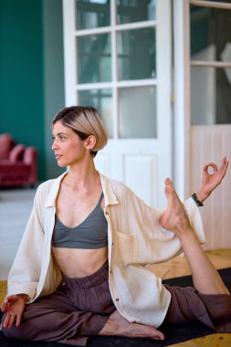 Esnek, sağlıklı bir kadın. Evde yoga yapıyor. Vücudunu esnetiyor.