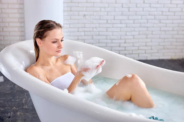 Femme dans le bain s'amuser, tenant la mousse dans les mains, regardant rêveur, appréciant — Photo