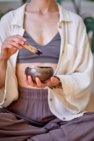 Обрезанная самка держит жгучую палочку с дымом на миске, медитирует, йогу — стоковое фото