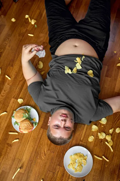 Vista dall'alto sul ragazzo grasso sdraiato sul pavimento in soggiorno, giovane ragazzo adolescente caucasico — Foto Stock