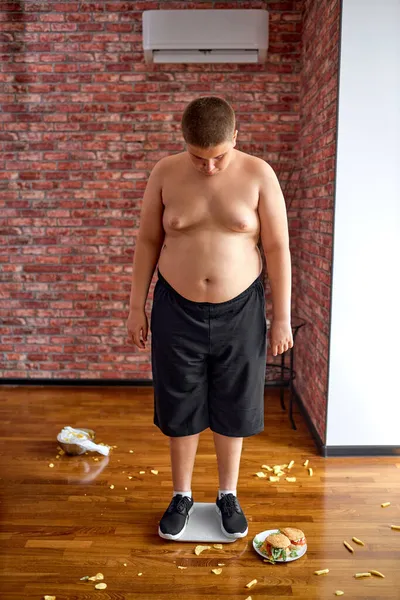 Menino com excesso de peso perturbado após a pesagem. Adolescente precisa perder algum excesso de peso. — Fotografia de Stock