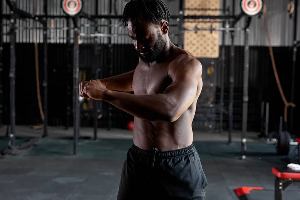 Joven atleta africano cuerpo masculino estiramiento, el calentamiento de los músculos, en el gimnasio — Foto de Stock