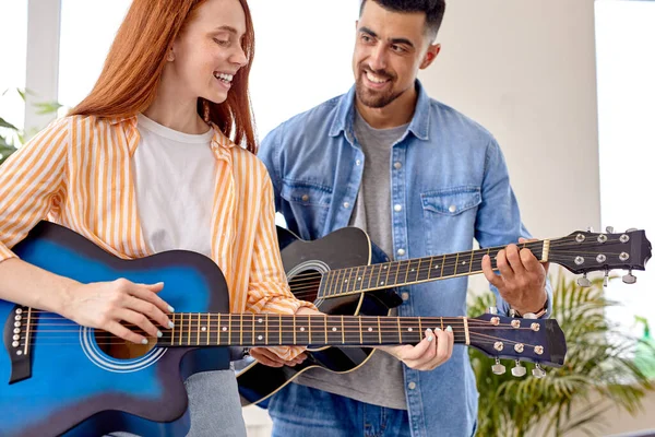 Красивая красавица и мужчина держат в руках гитару, учат новый аккорд — стоковое фото