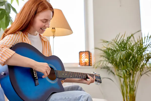 Portrait de jeune rousse femelle dans l'usure occasionnelle jouant de la guitare, à la maison — Photo
