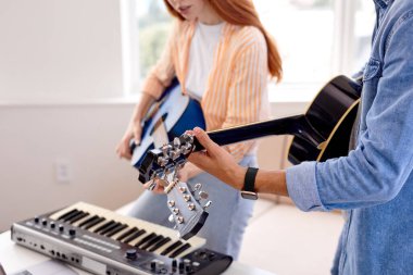 Kırpılmış beyaz adam, kız arkadaşıyla birlikte gitar çalıp şarkı söylüyor.