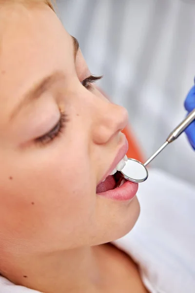 Вид збоку приваблива біла дитина, що відвідує стоматолога, лікар робить огляд зубів — стокове фото