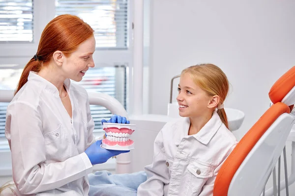 Stomatolog i uniform med käkmaket berättar om vården på tandvårdskliniken — Stockfoto