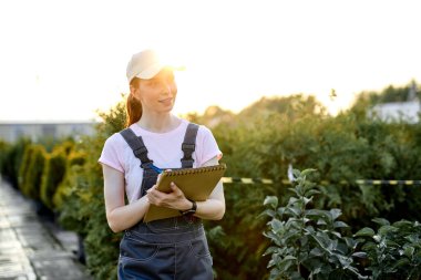 Serada çalışan, üzerinde not defteri olan, üniformalı, kızıl saçlı bir kadın araştırmacı.