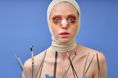 Burun kıvrımları olan genç bir kadın burun kıvrımlarına iğne yapar, portreyi kapatır.