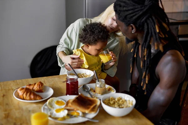 Όμορφο μαύρο παιδί πίνει φρέσκο χυμό στο πρωινό κάθεται με τους γονείς, την οικογένεια — Φωτογραφία Αρχείου