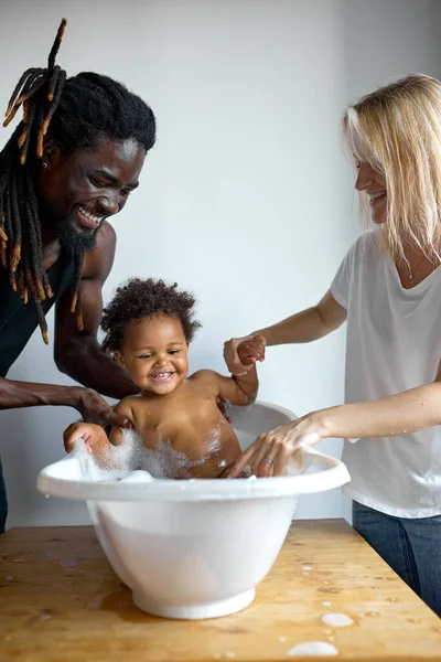 Mère et père laver la petite fille dans la baignoire, enfant amusez-vous, souriant — Photo