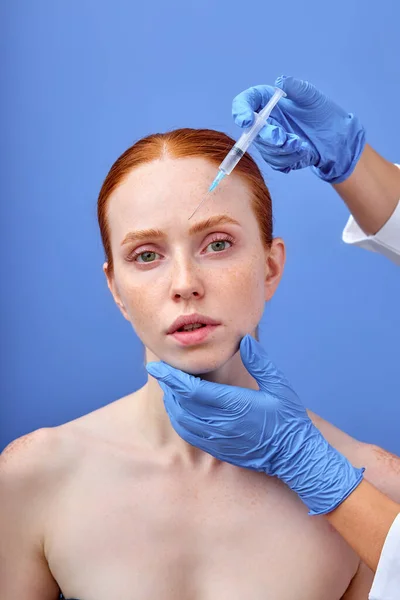 Cropped view of plastic surgeon in gloves holding syringe near face of woman — Stock Photo, Image