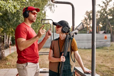 Beyaz kulaklıklı hoş bir erkek, kadınlara silah kullanmayı öğretiyor.
